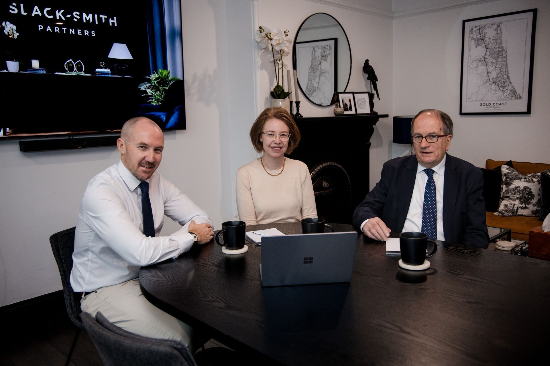 Three People Sit at a Dark Table. Two Men and a Woman Face the Camera, Indoors — Slack-Smith Partners In Moree, NSW