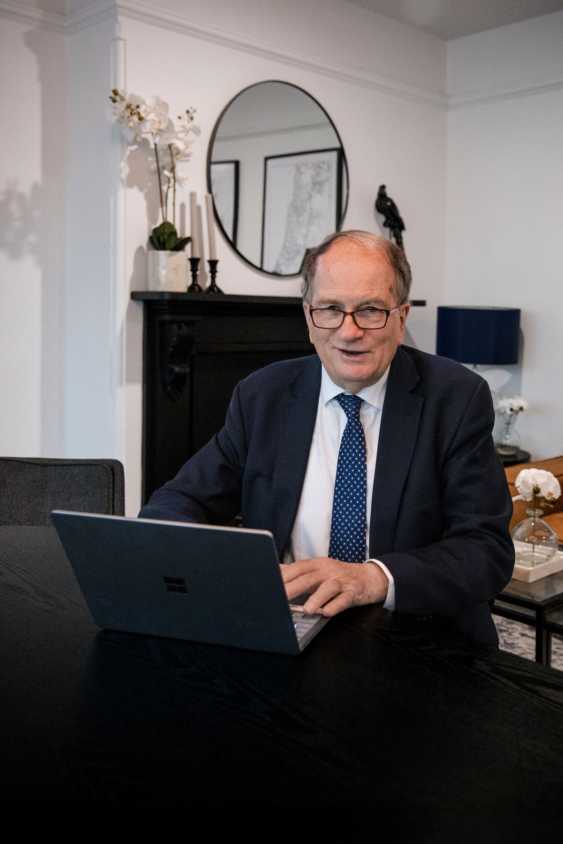 Man in Suit at a Desk, Looking at a Laptop. Sitting in Front of a Fireplace — Slack-Smith Partners In Moree, NSW