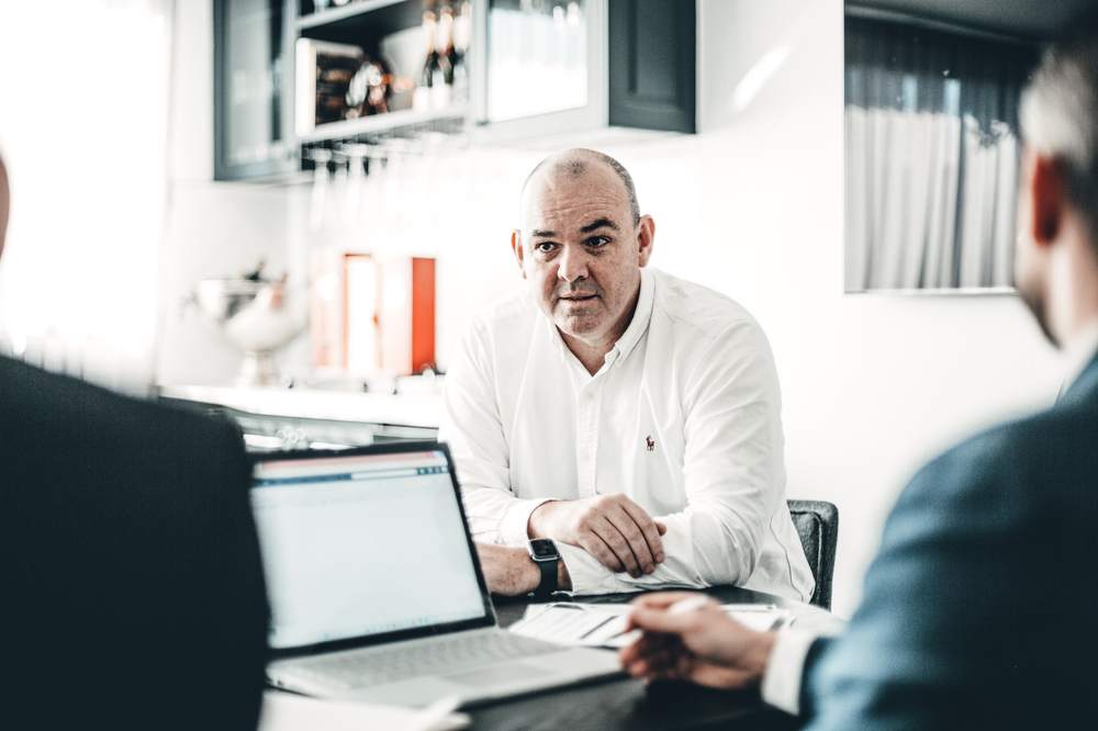 A Group of Men Are Sitting at A Table With Laptops — Slack-Smith Partners in Tamworth, NSW