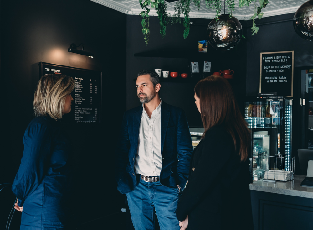 A Group of People Are Standing in A Dark Room Talking to Each Other — Slack-Smith Partners in Tamworth, NSW
