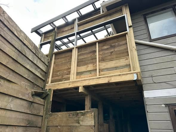 Wooden deck with weathered wood siding on a house; partially enclosed with a roof.