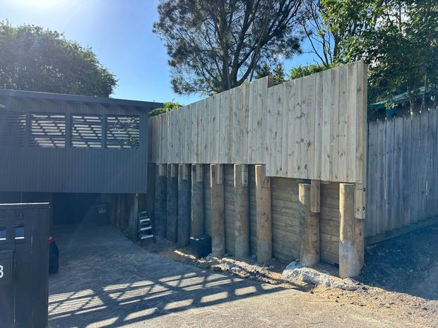 Wooden retaining wall with vertical posts and wood plank fence.