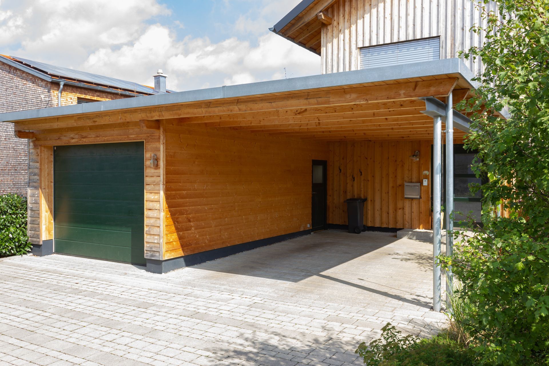 Wooden carport with a green garage door.