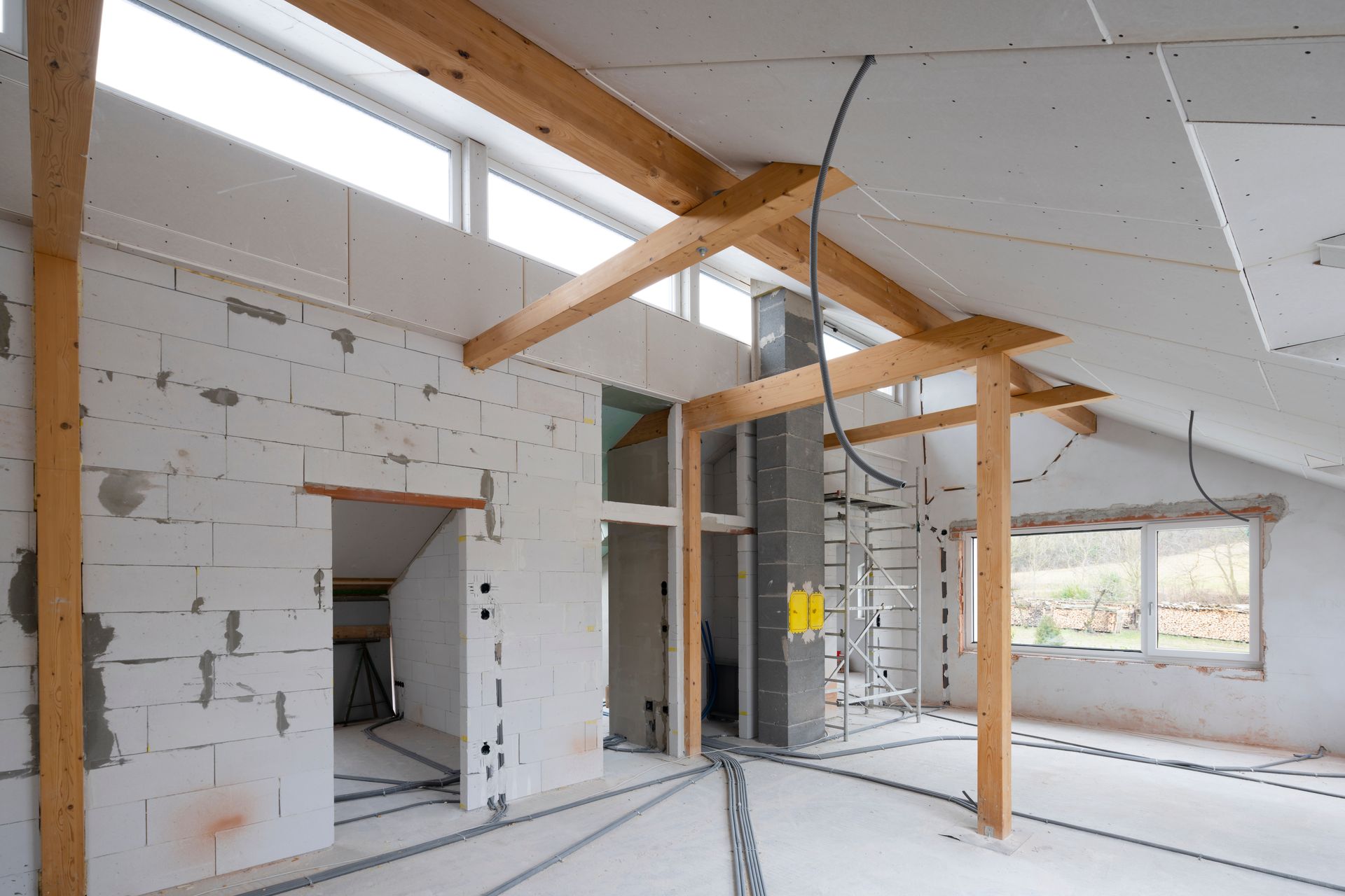 Interior of a building under construction, showing exposed wooden beams, concrete blocks, and wiring. Interior of a building under construction, showing exposed wooden beams, concrete blocks, and wiring.