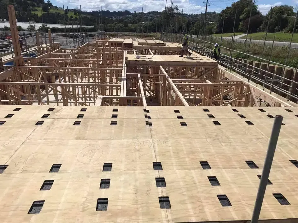 Wooden building under construction with exposed framing and plywood flooring.