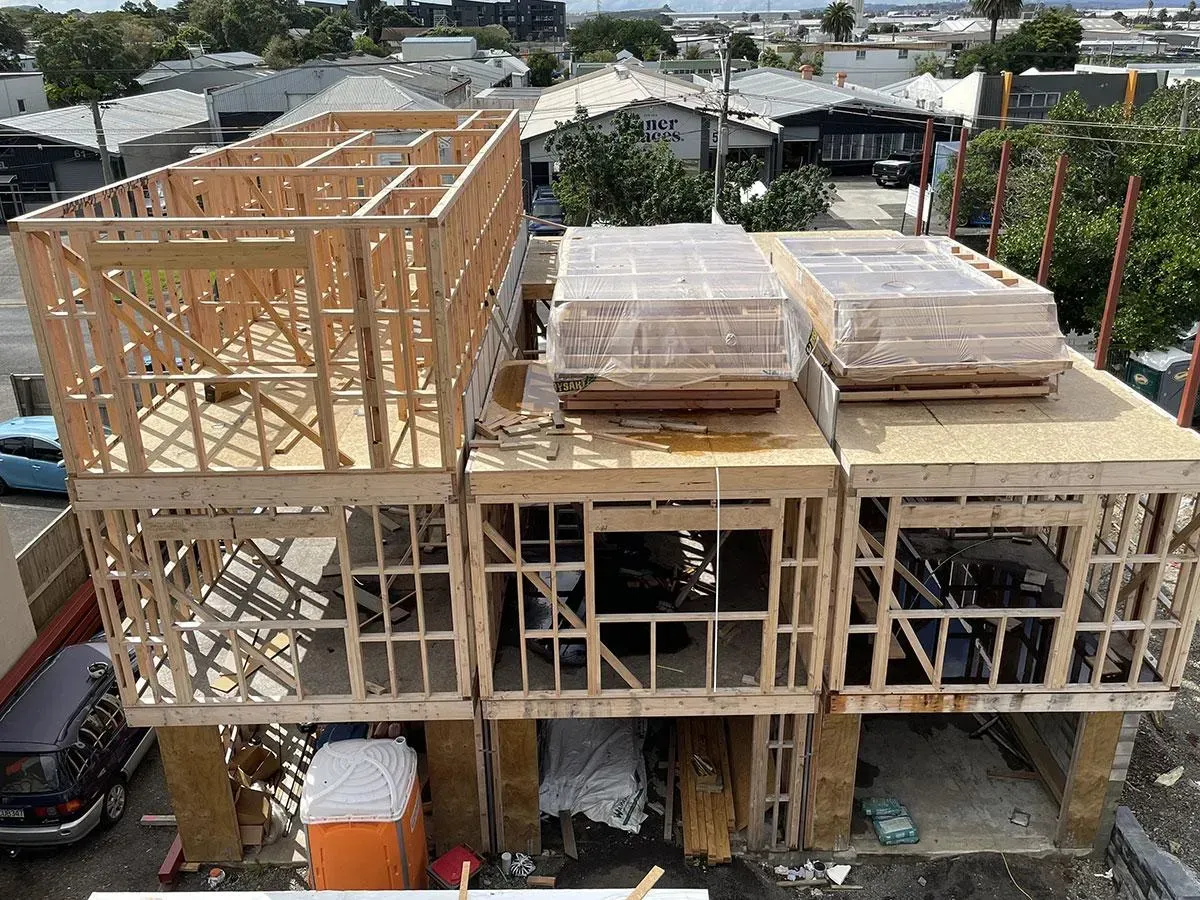 Wood frame construction of a multi-unit building with unfinished second stories and flat roofs.