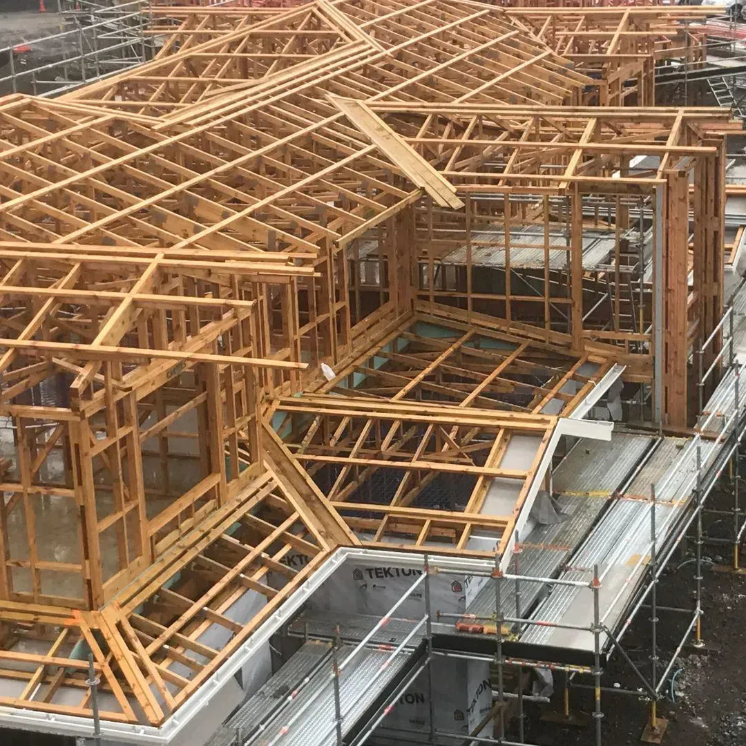 Wooden framework of a building under construction, with exposed beams and scaffolding.