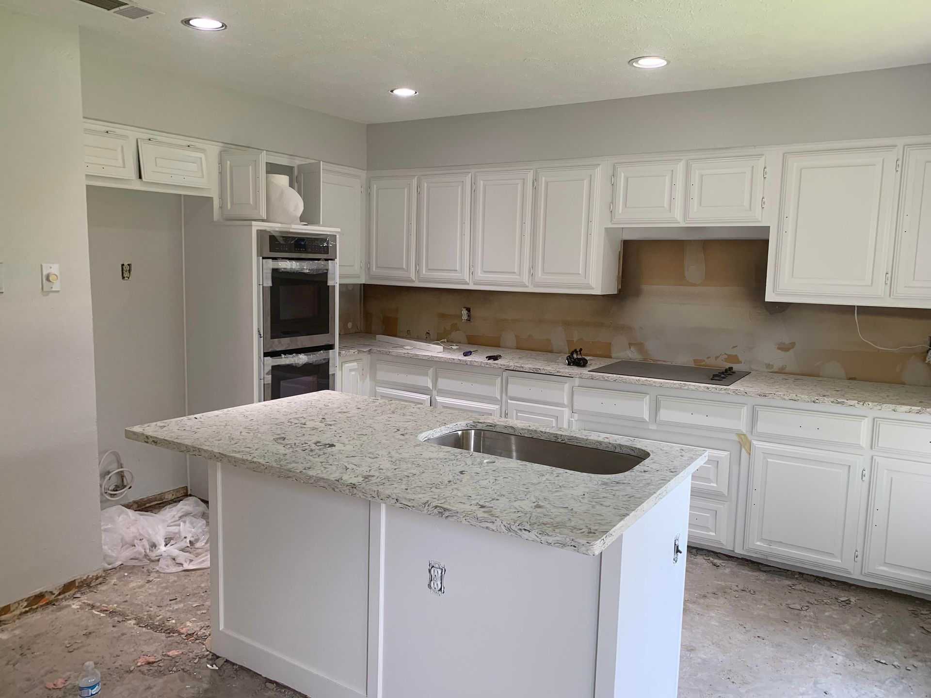 A kitchen with white cabinets and granite counter tops is being remodeled.