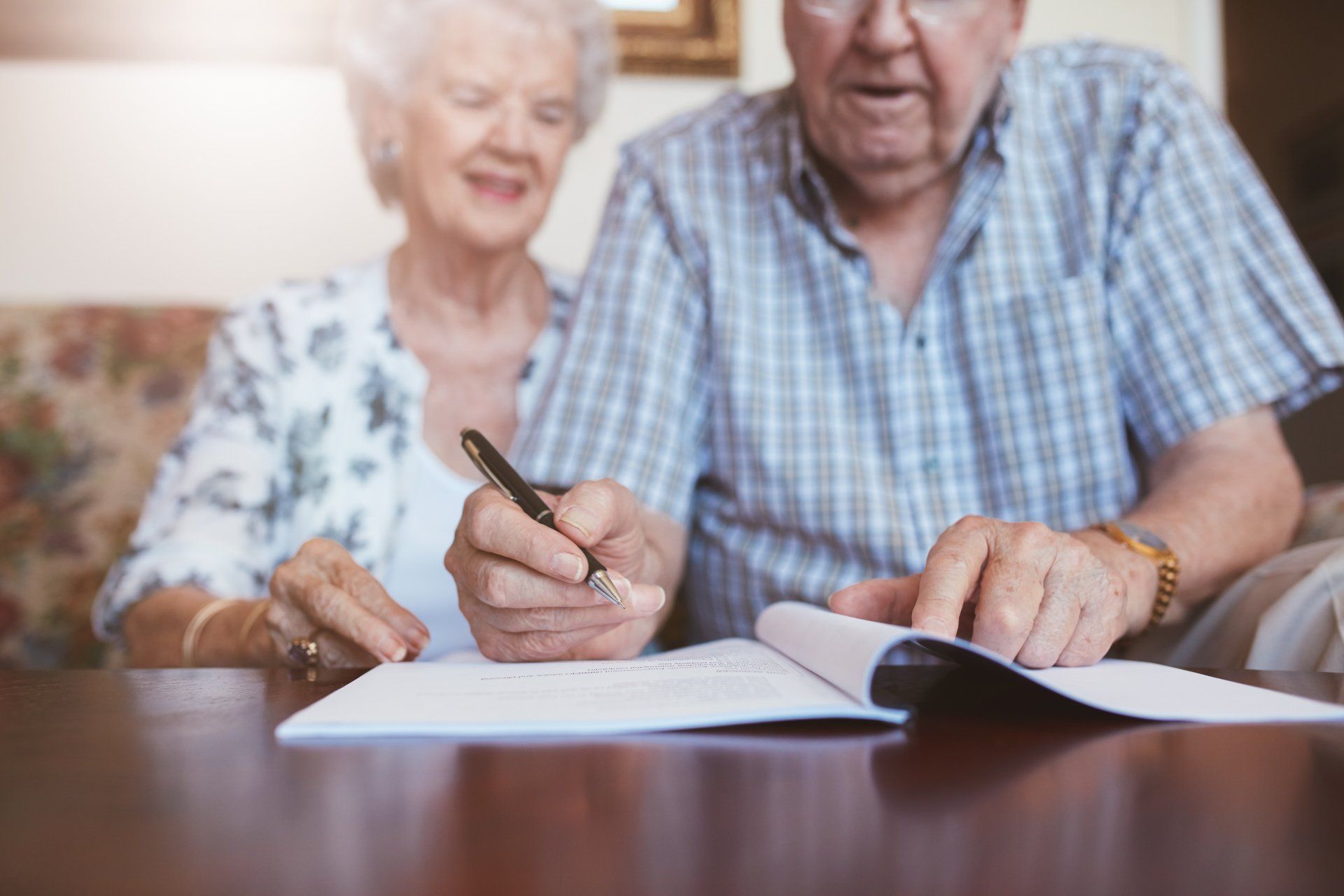 an elderly couple is sitting at a table filling out legal documents.