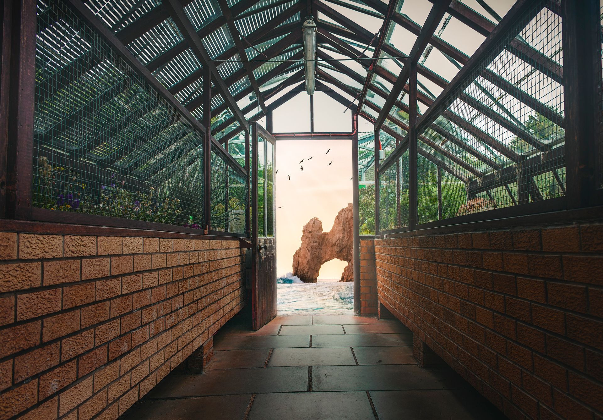 A greenhouse with a brick wall and a glass roof.