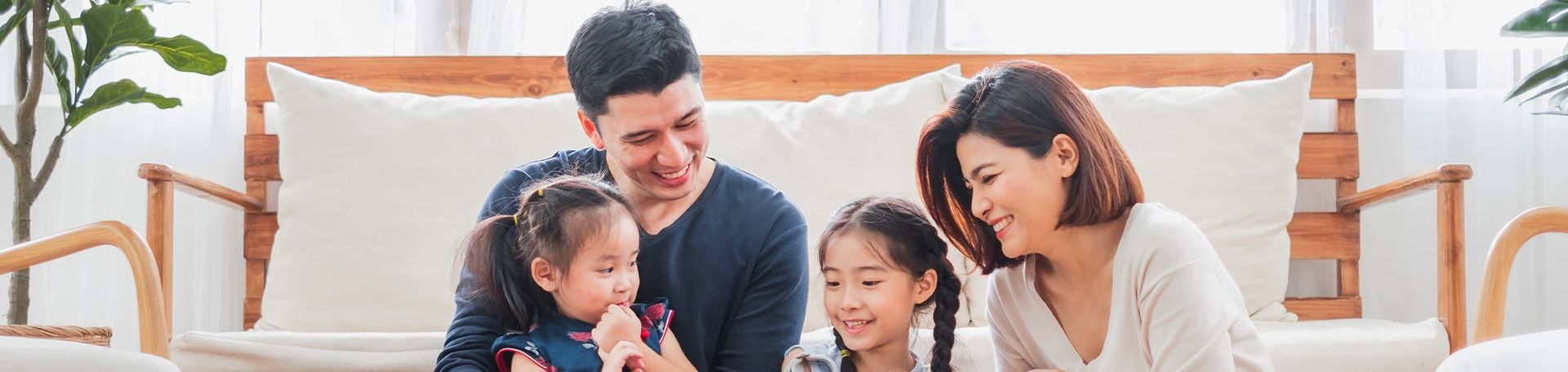 Family of four smiling together in a living room.