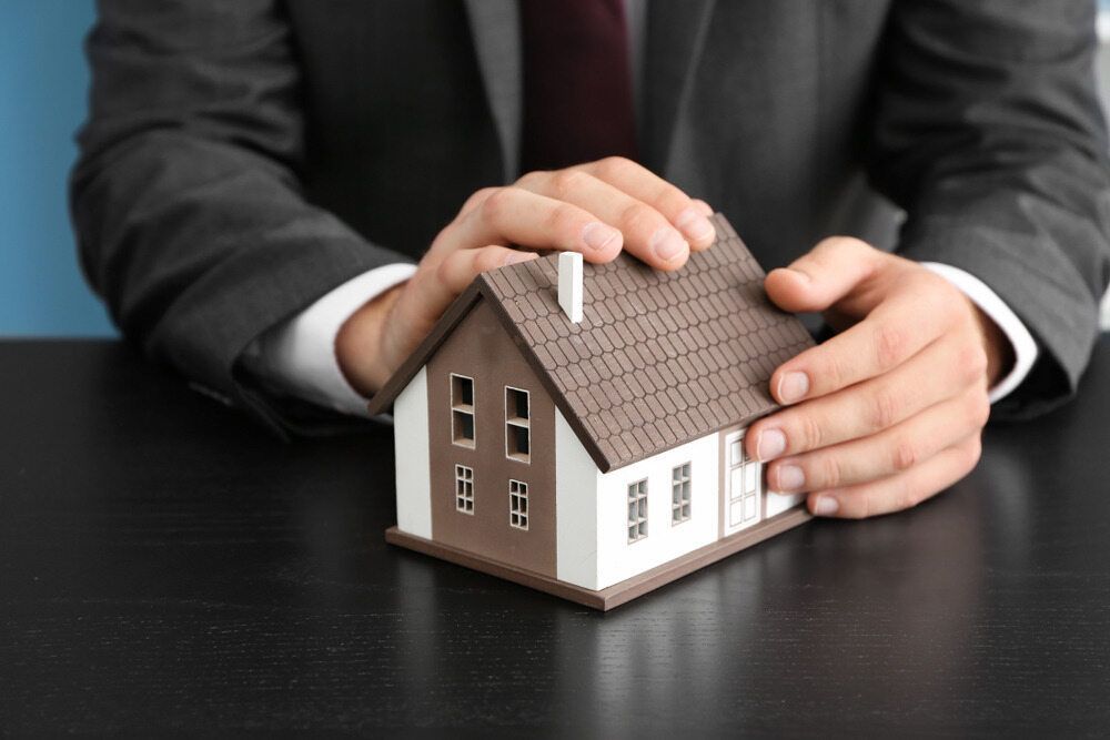 A Man in a Suit and Tie is Holding a Model House in His Hands — Murphy Finance Solutions–Darwin & Palmerston In Zuccoli, NT