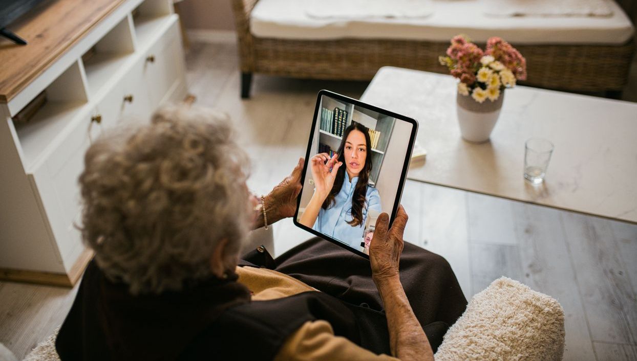 Elderly woman on tablet talking to younger woman