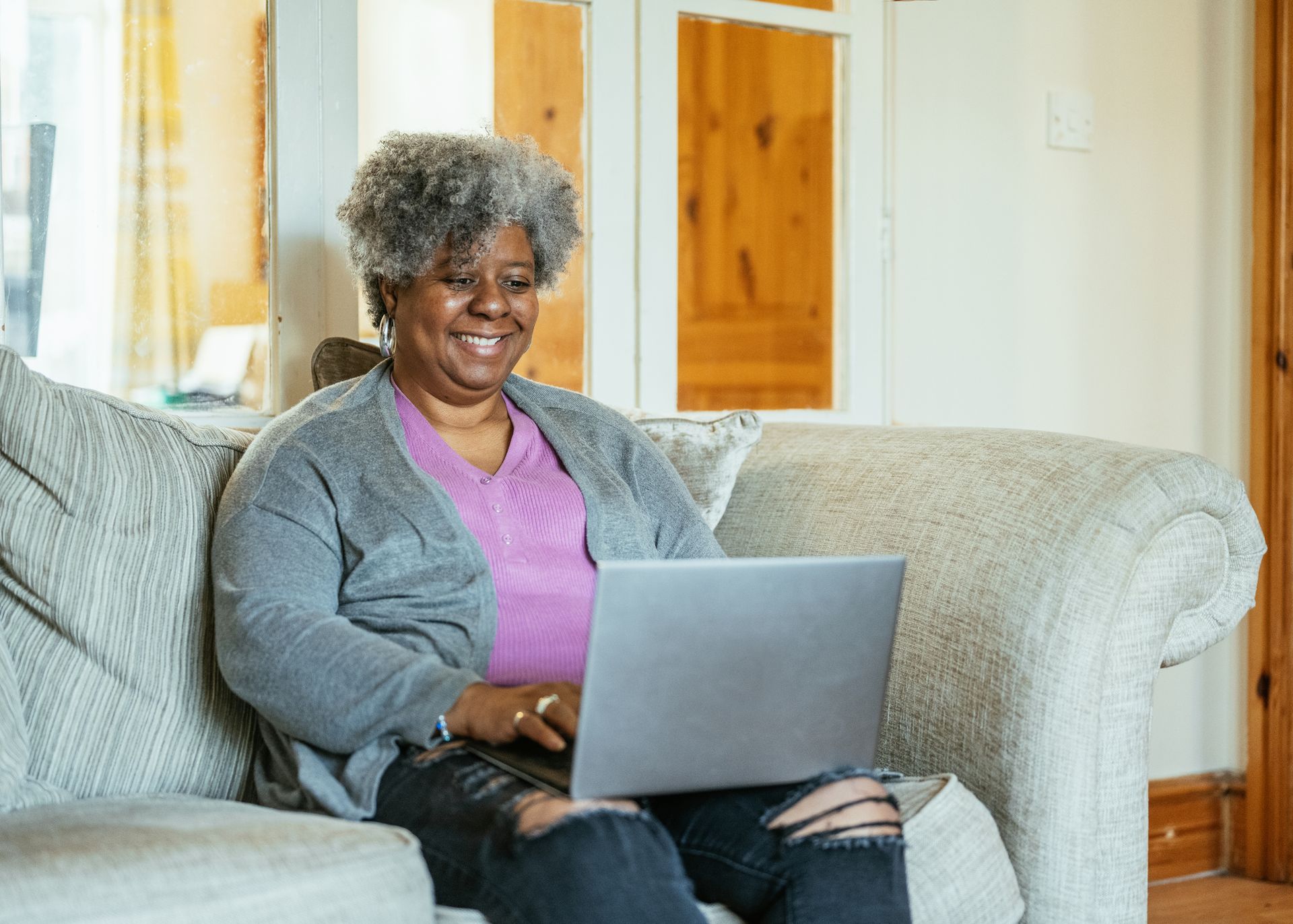 Elderly black woman on computer in home on couch