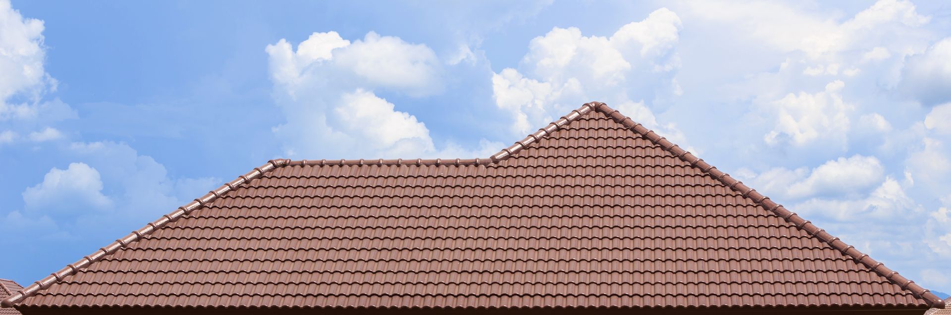 Brown tiled roof against a blue sky with white clouds.