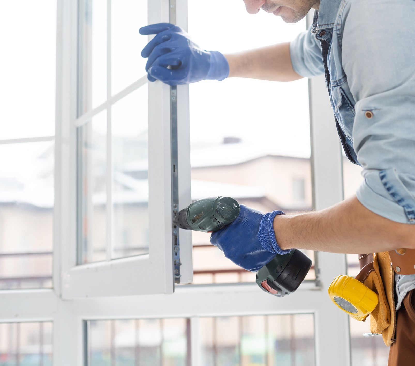 A man is using a drill to fix a window.