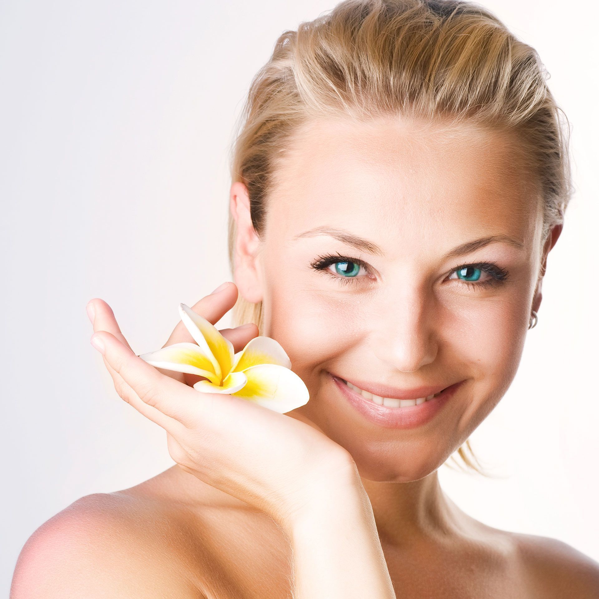 Eine Frau lächelt und hält eine Blume in der Hand