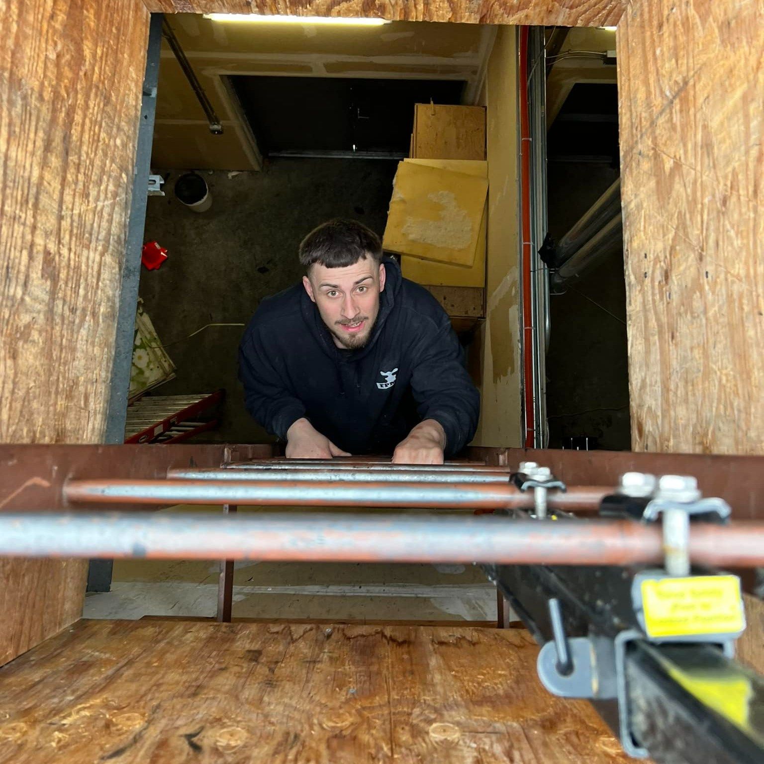 Construction workers in yellow hard hats and orange vests, smiling, posing together indoors.