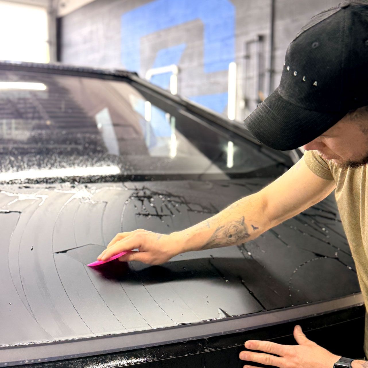 A person wearing black gloves is polishing the hood of a red car.