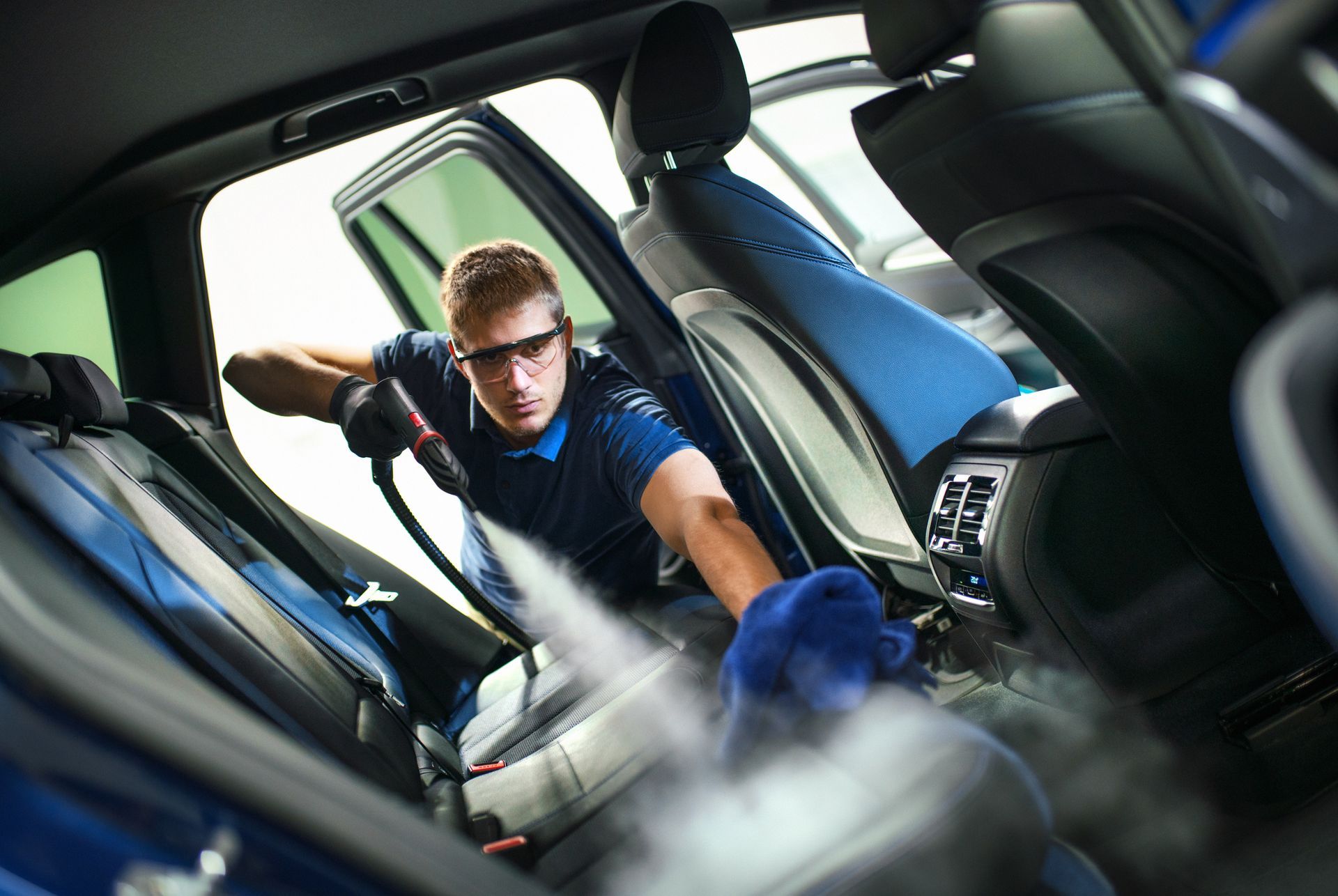 A man is cleaning the interior of a car with a vacuum cleaner.