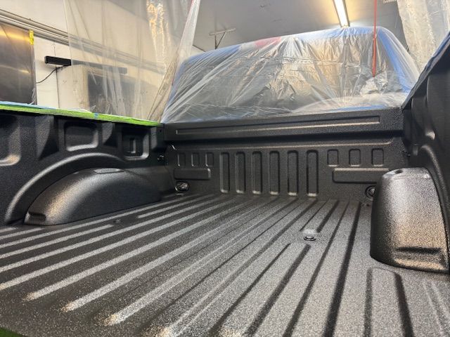 A person is using a brush to remove rust from a car fender.