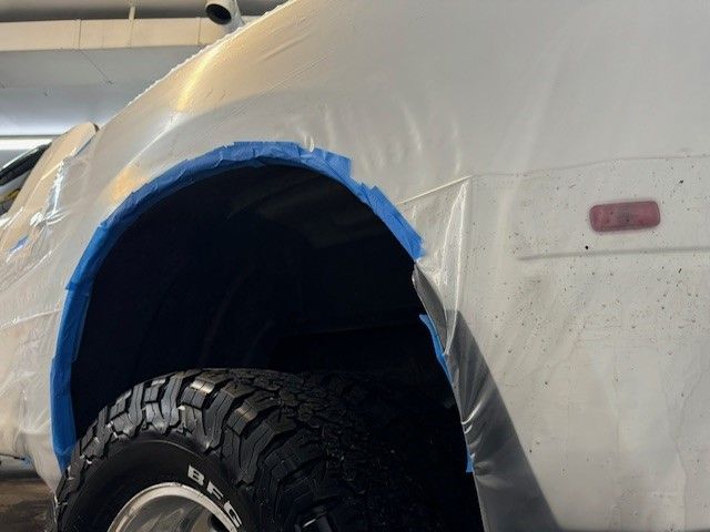 A close up of a red car with rust on the side. A close up of a red car with rust on the side.