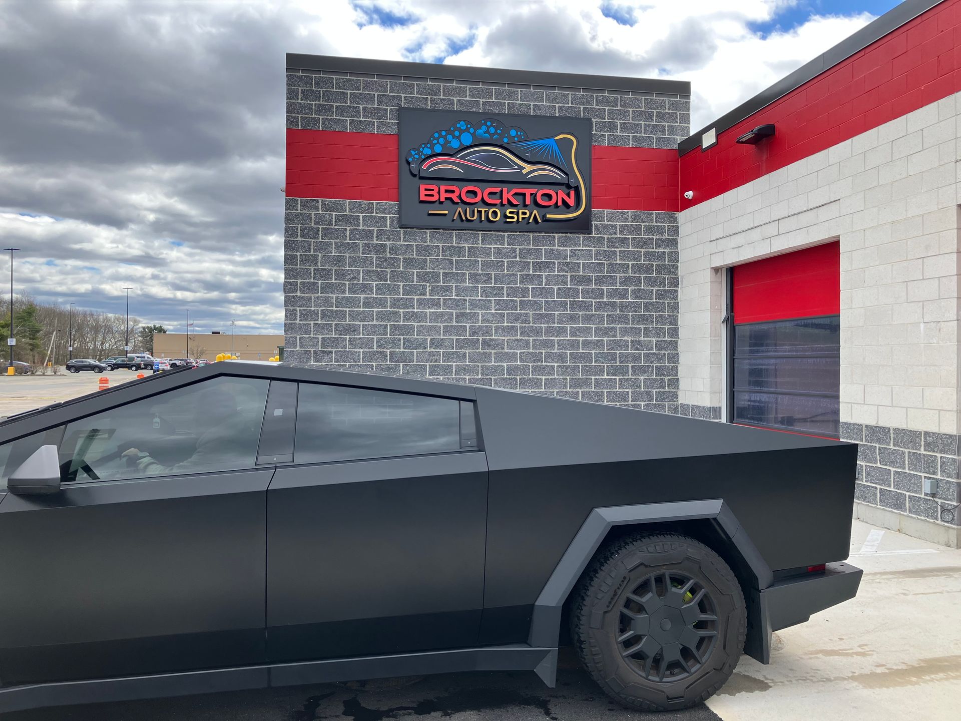 A black car is parked in front of a brick building.