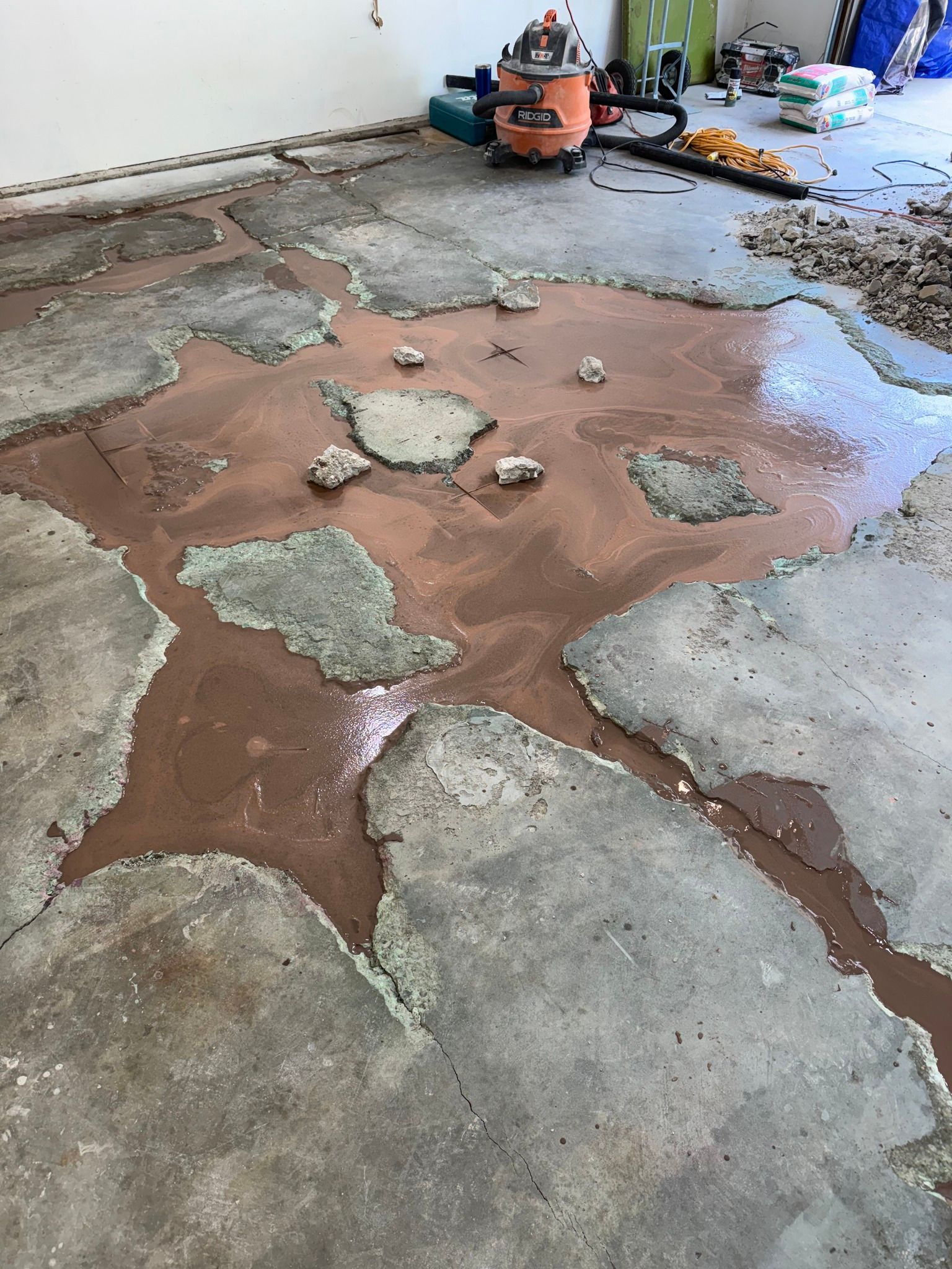 Floor being prepared, showing a concrete slab with a brown material applied to its surface.