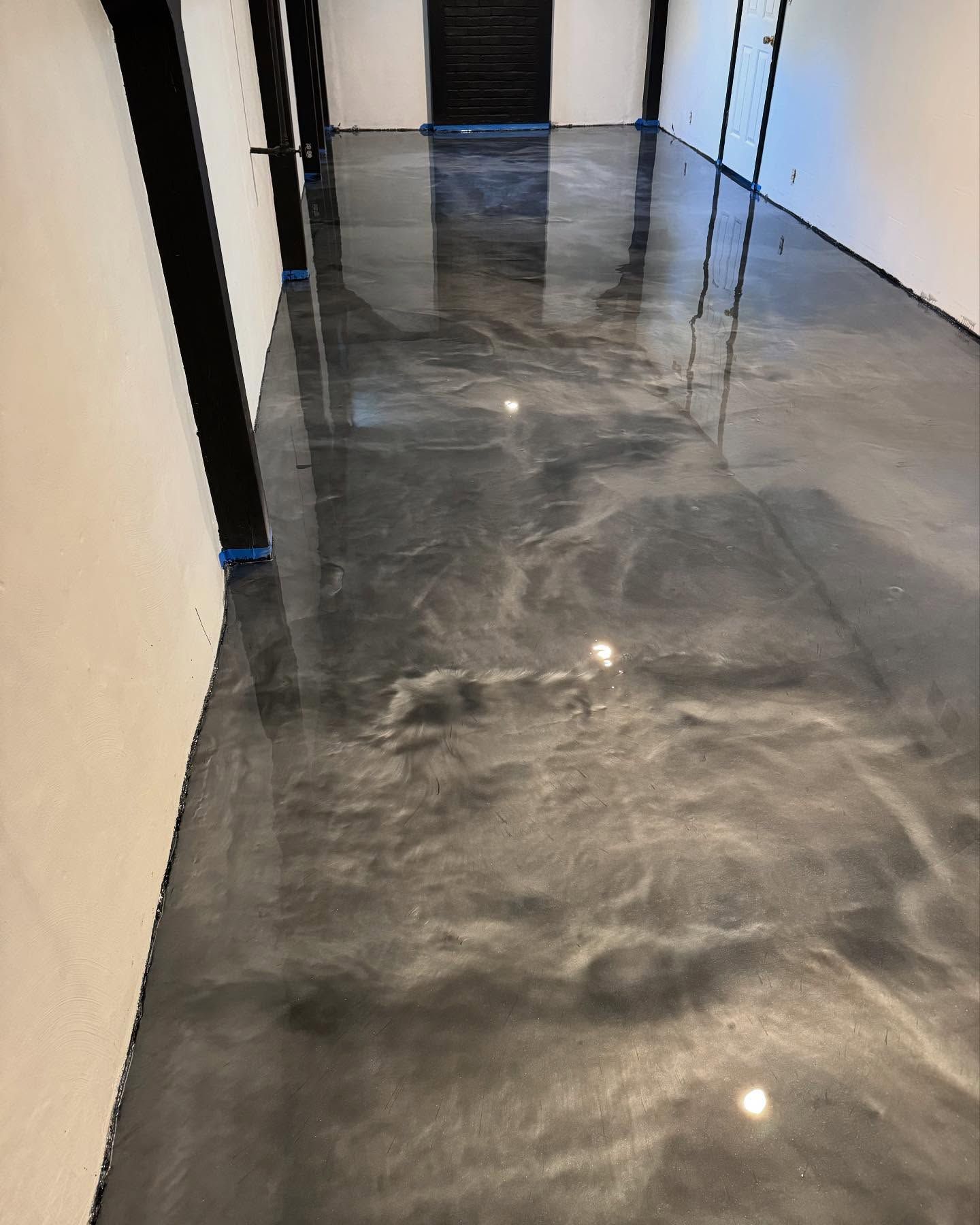 Metallic gray epoxy flooring in a room with white walls and dark wooden beams.