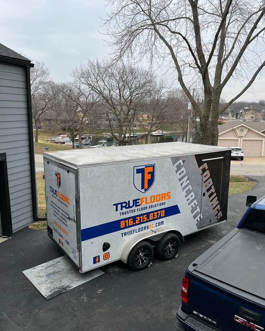 A trailer for True Floors flooring company parked in a driveway.