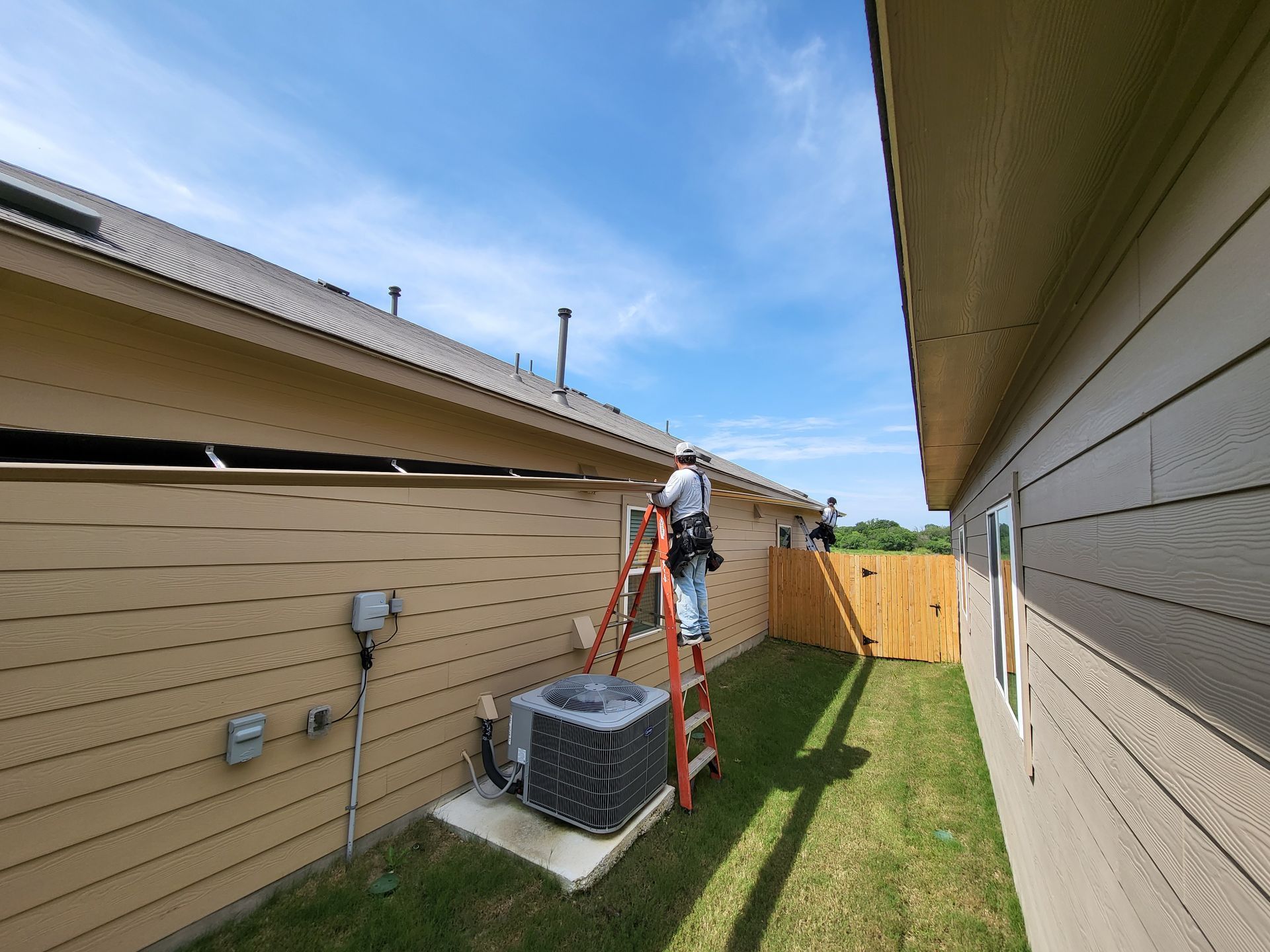 Advanced Seamless Rain Gutter Solutions crew installing seamless gutters along side of the house