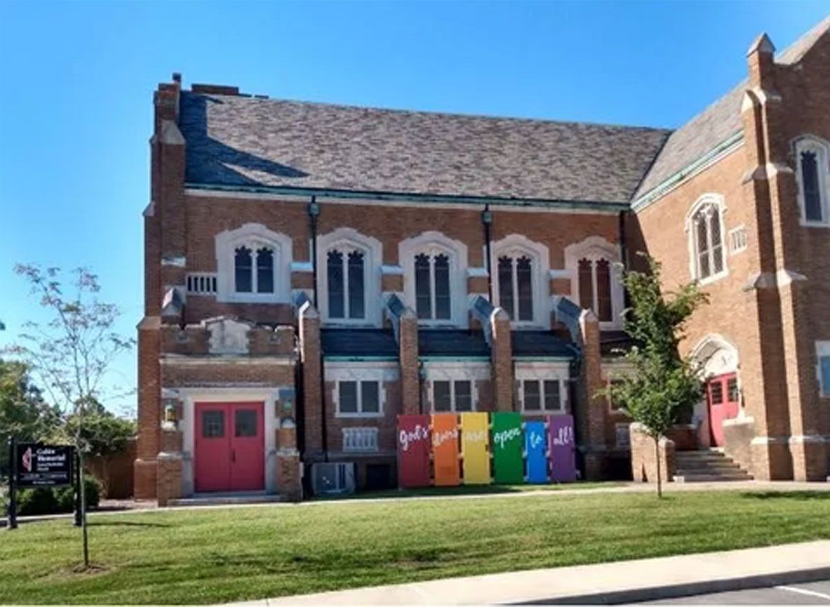 Brick building with colorful rainbow-painted doors and a sidewalk in front