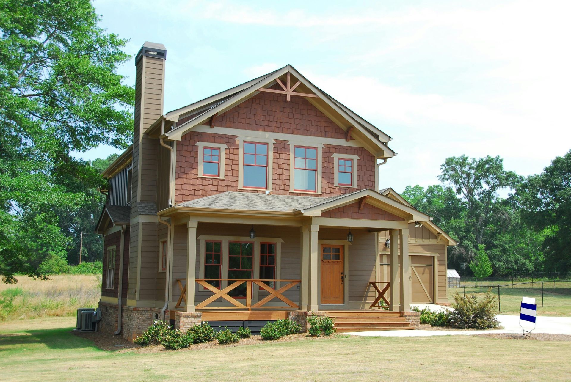 Two-story Craftsman home with porch, red brick accents, and a garage.