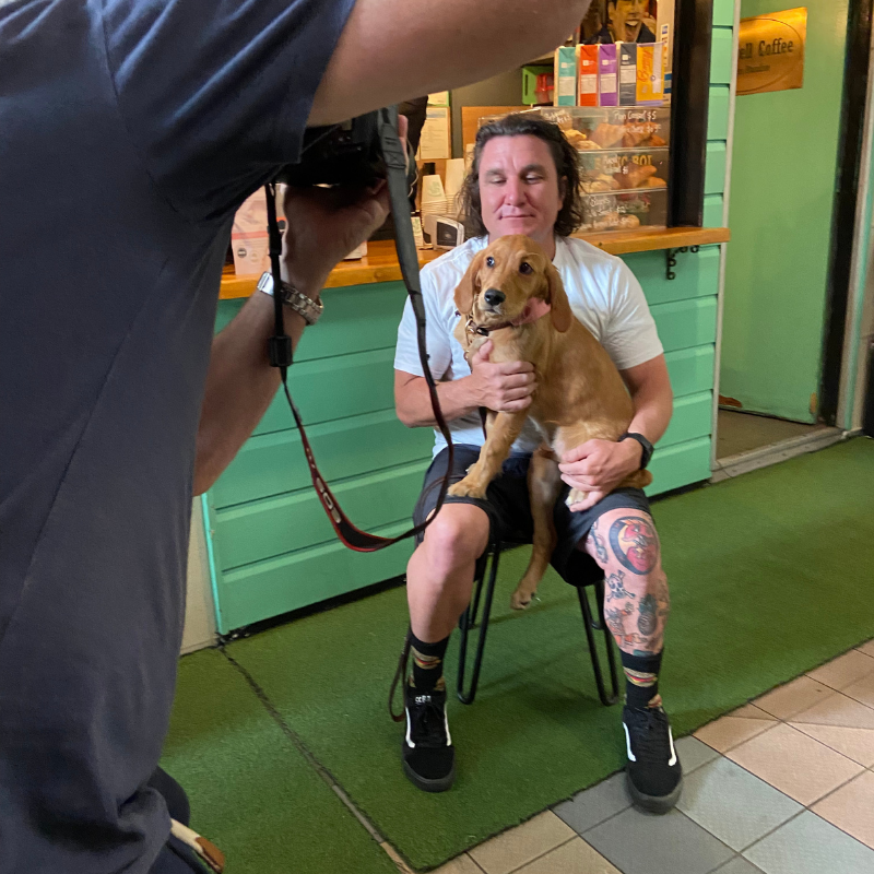 A man is taking a picture of a woman holding a dog