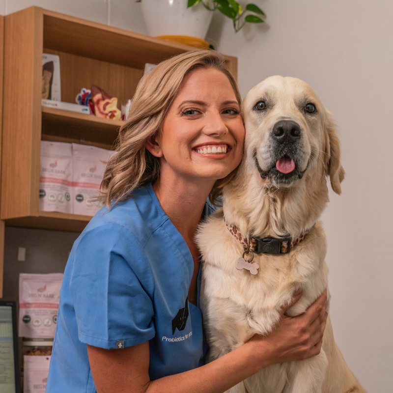 A woman in a blue scrub is hugging a dog