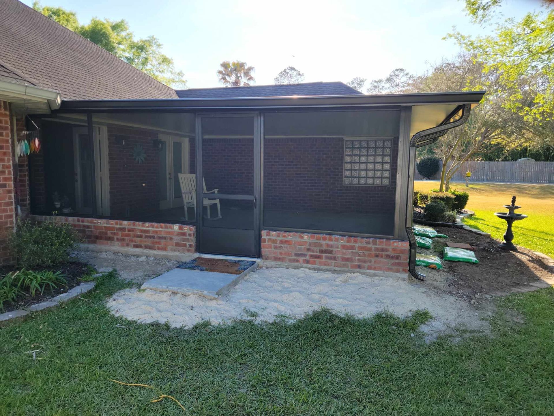 There is a screened in porch in the backyard of a house.