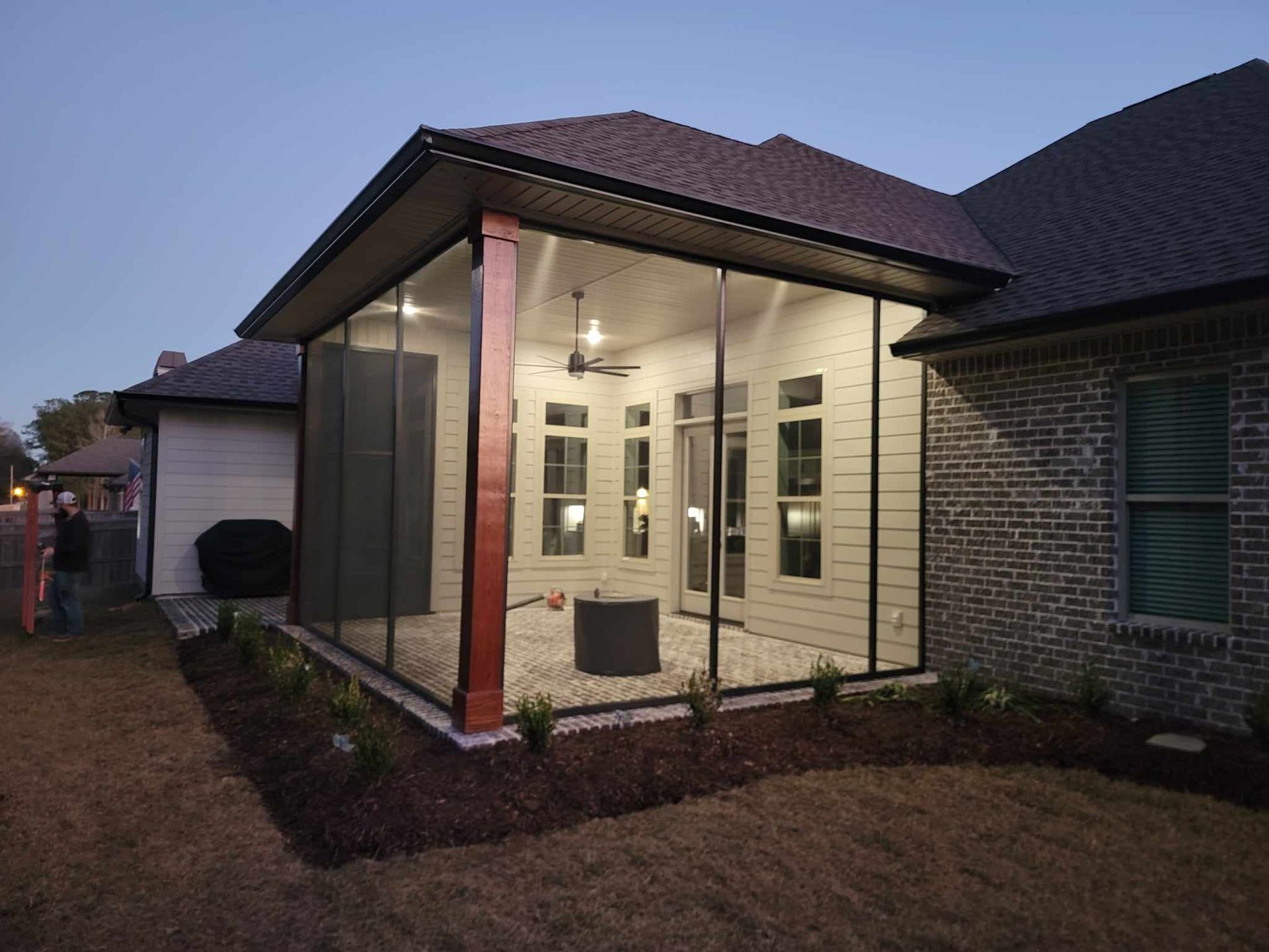 A screened in porch with a brick house in the background