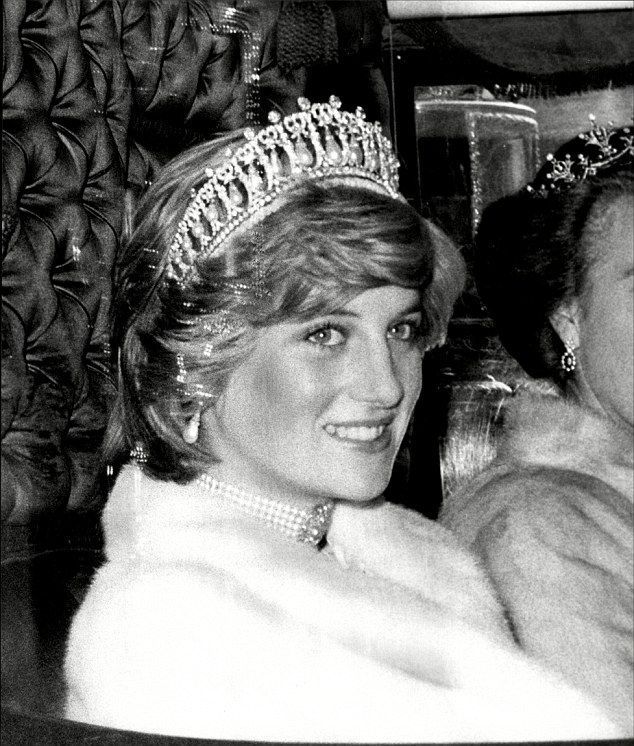Woman wearing a tiara and pearl necklace smiles, in a car, with a white fur wrap.