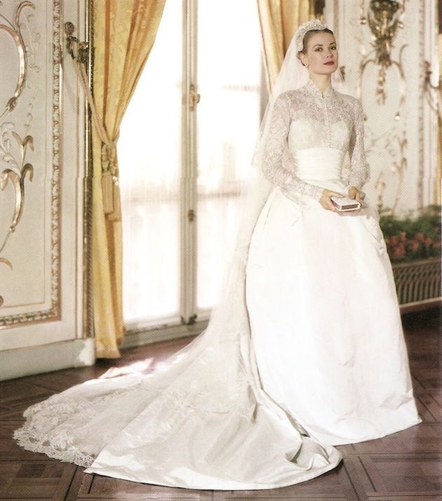Grace Kelly in her wedding dress, standing in a room with ornate decor, holding a small object.