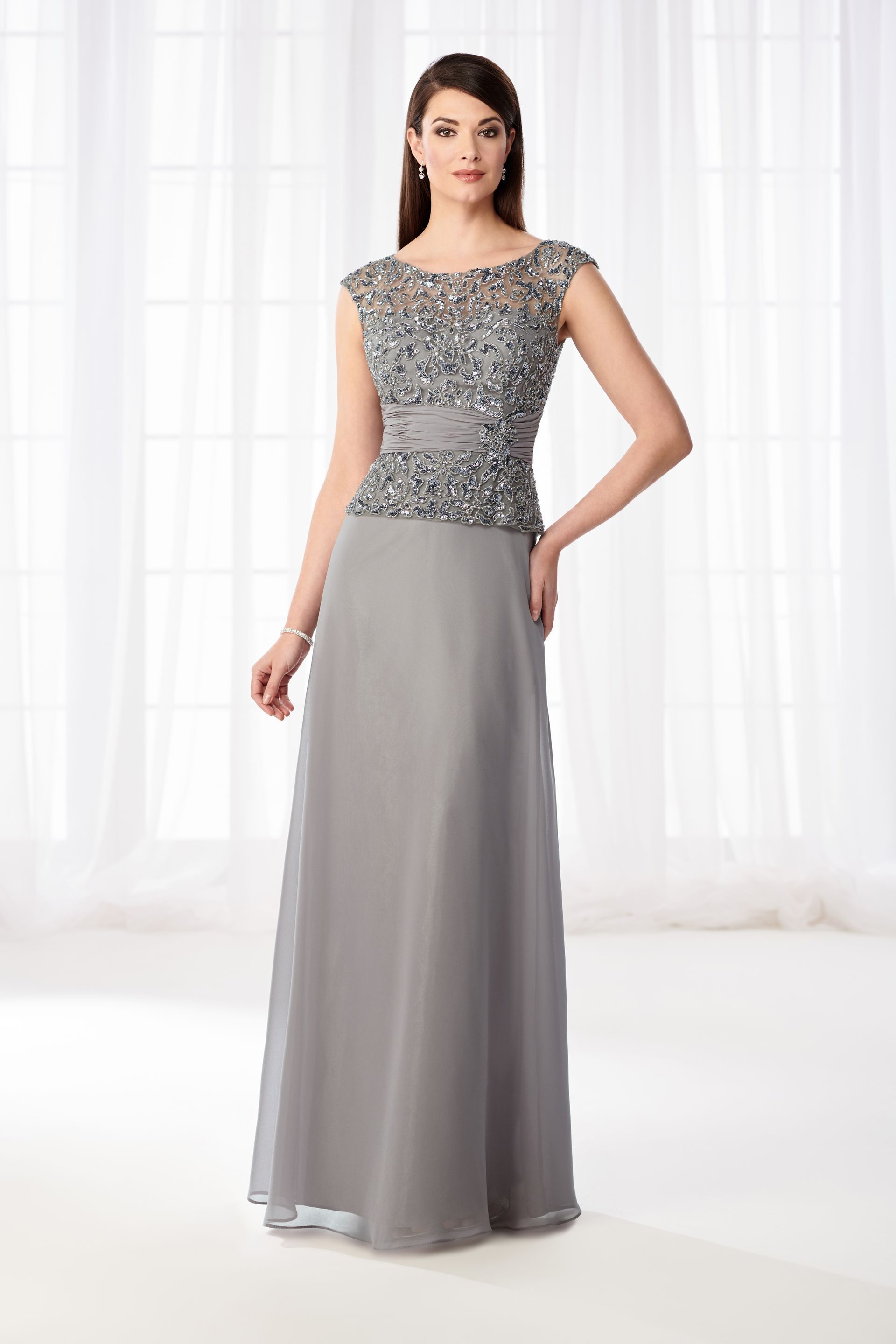 Woman in gray evening gown with beaded bodice, standing indoors.