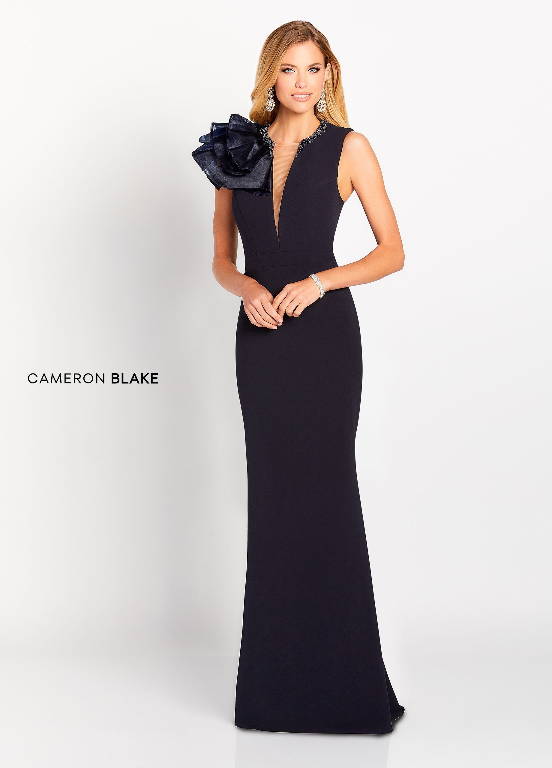 Woman in a navy formal gown with a large shoulder flower detail.