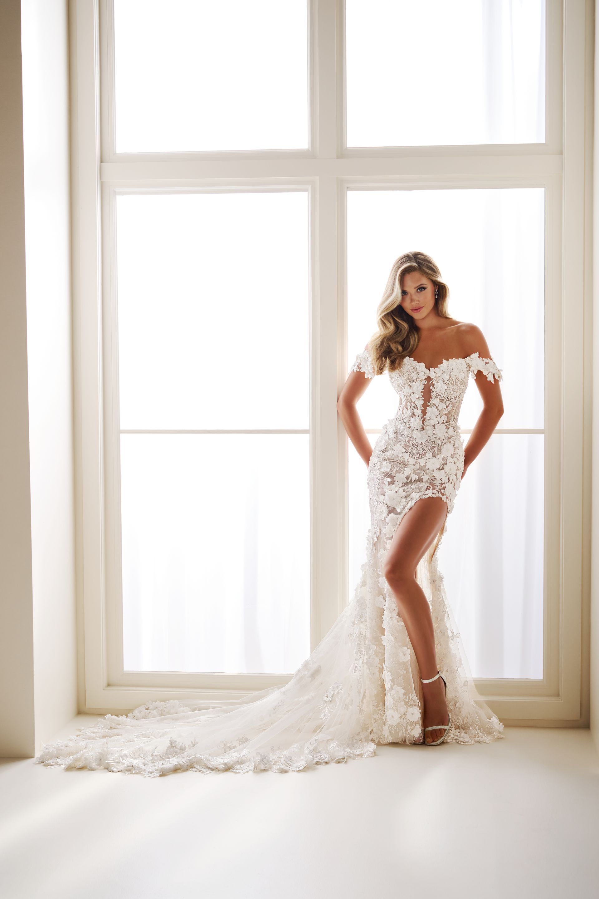 Woman in white lace dress by a window, dress with long train.