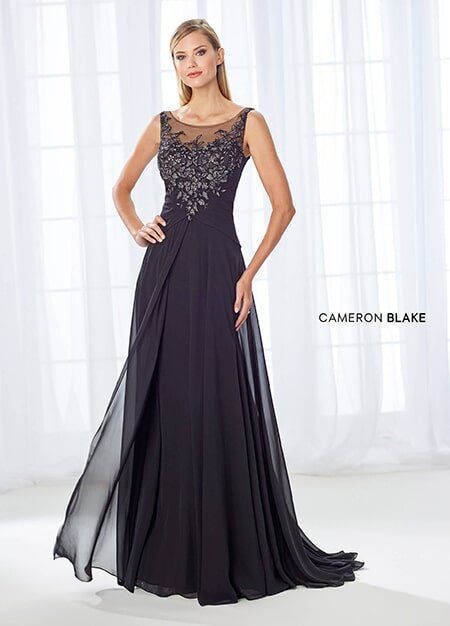 Woman in a dark formal gown with sheer overlay; intricate bodice detail.