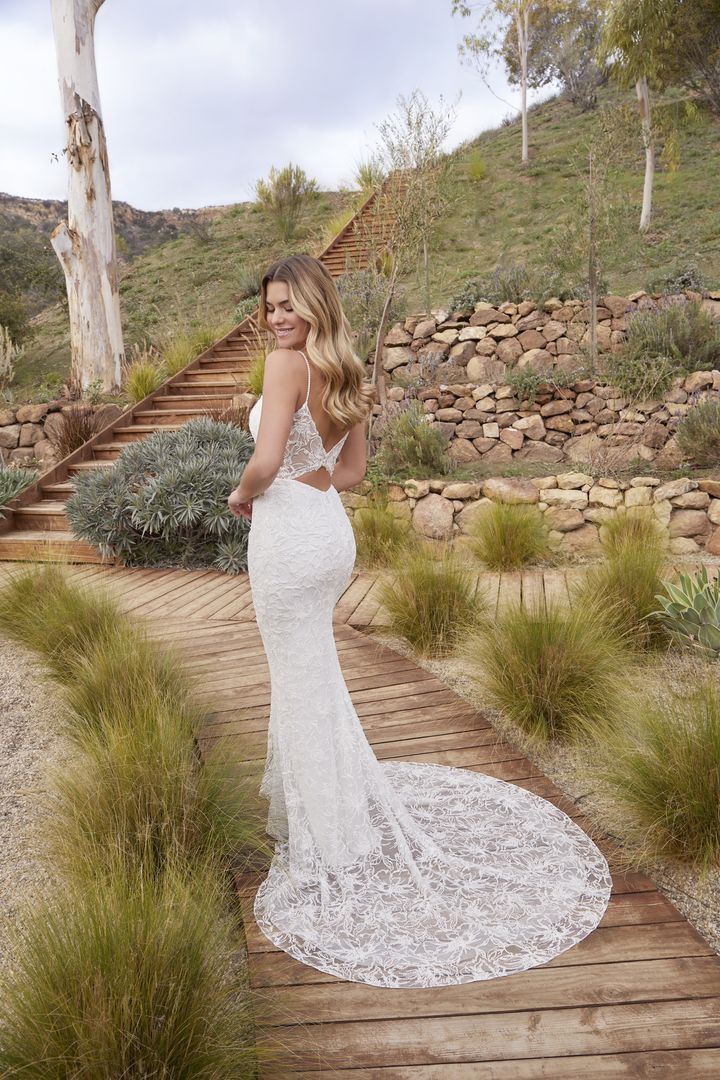 Woman in a beaded white wedding dress on a path with a long train.