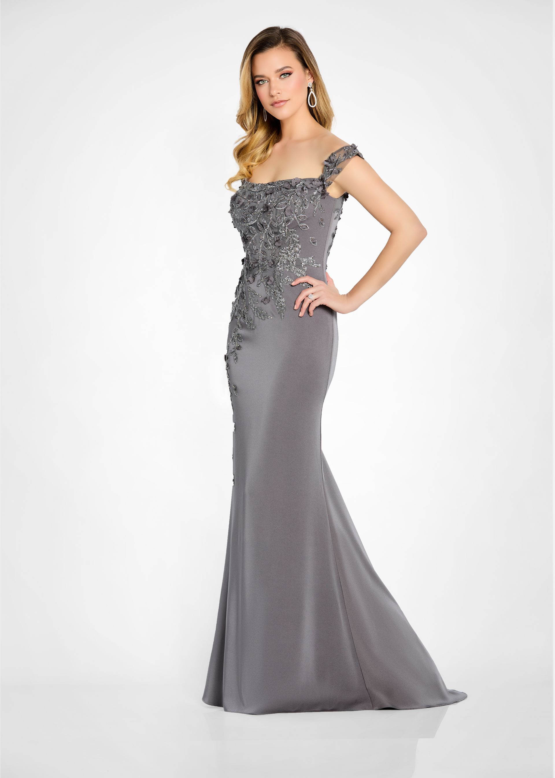 Woman wearing a gray formal gown with embellished bodice and shoulder straps, posing indoors.