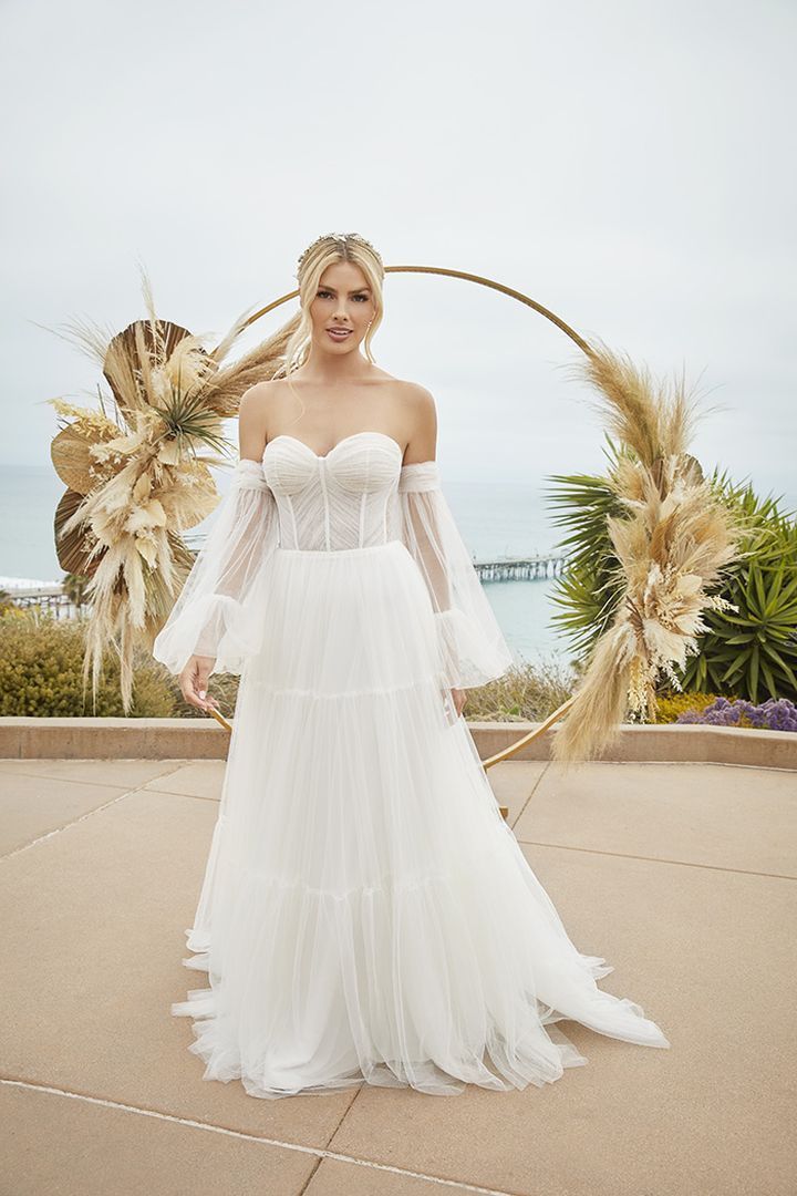 Woman in white wedding dress posing in front of an arch with ocean view.