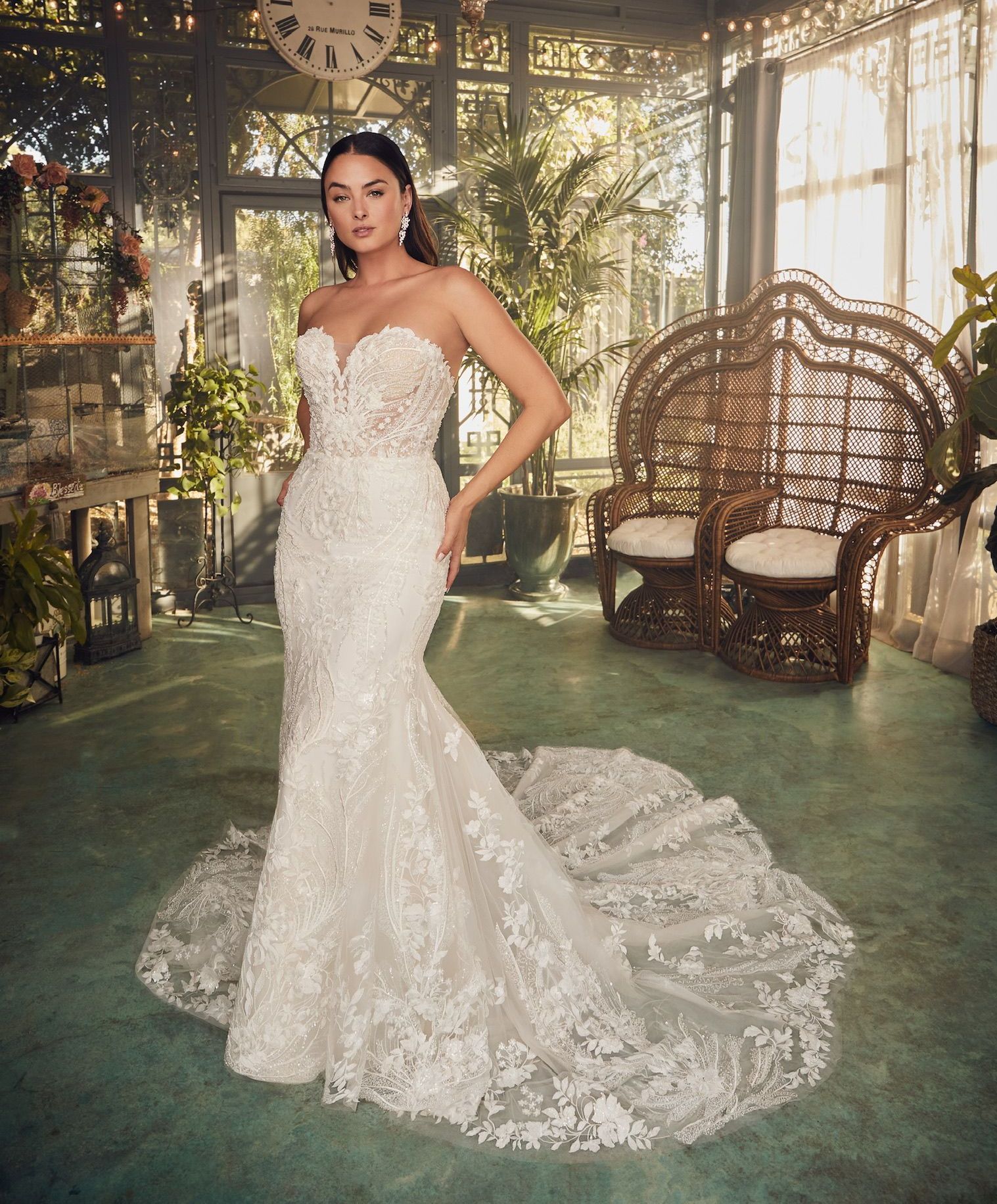 Woman in white strapless lace wedding dress, in a sunlit indoor garden setting.