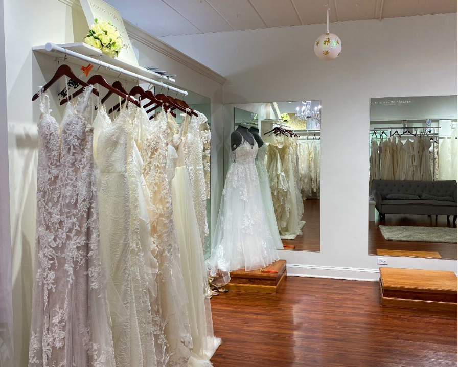 Wedding dresses hanging in a bridal shop, with mirrors and wooden floors.