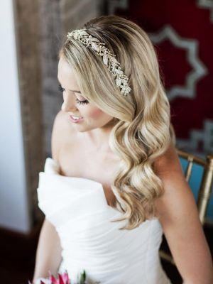 Blonde-haired woman wearing a white wedding dress and decorative headband, wavy hair, soft makeup.