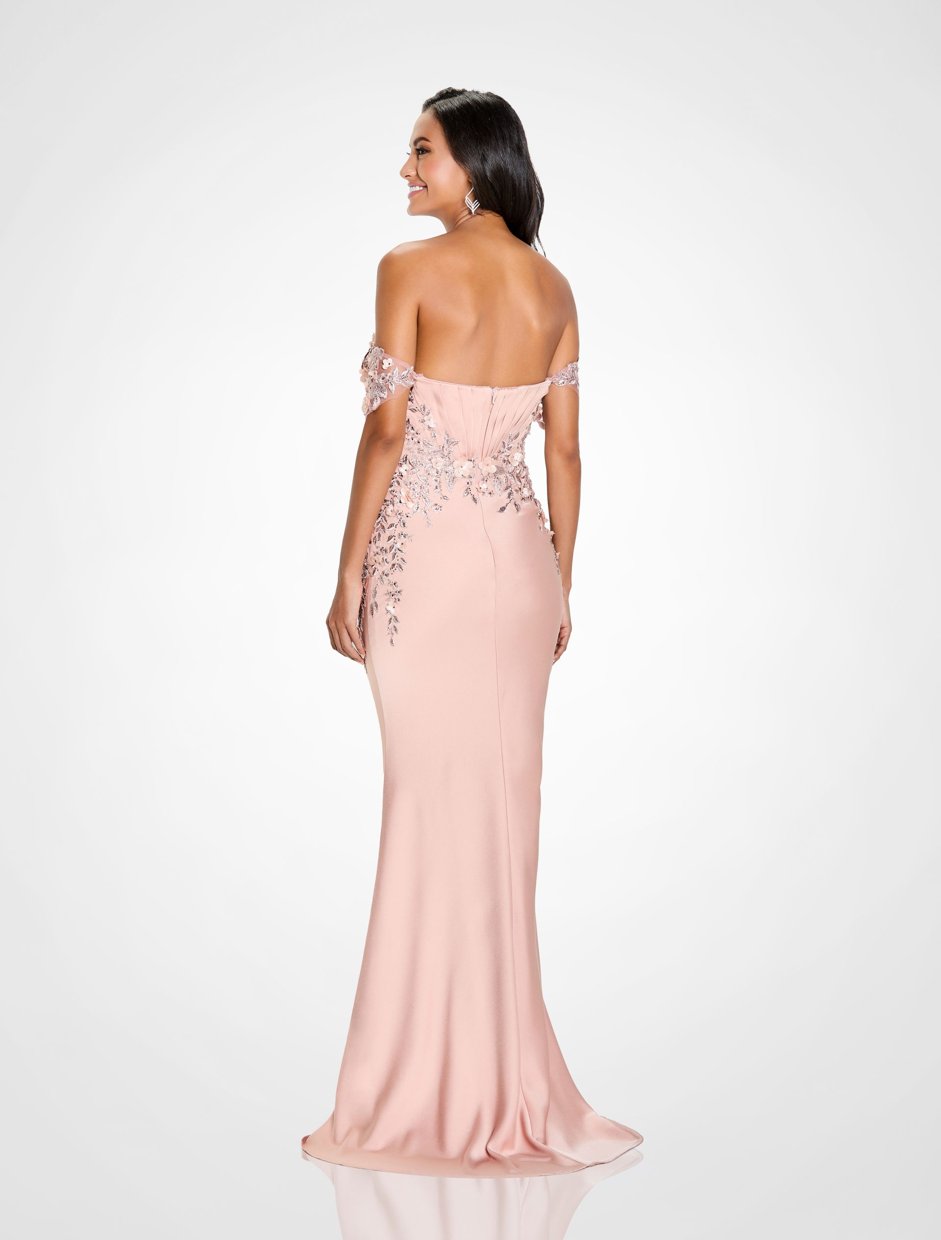 Woman in a gray, formal gown posing against a white backdrop. Dress features embellished bodice and mermaid skirt.